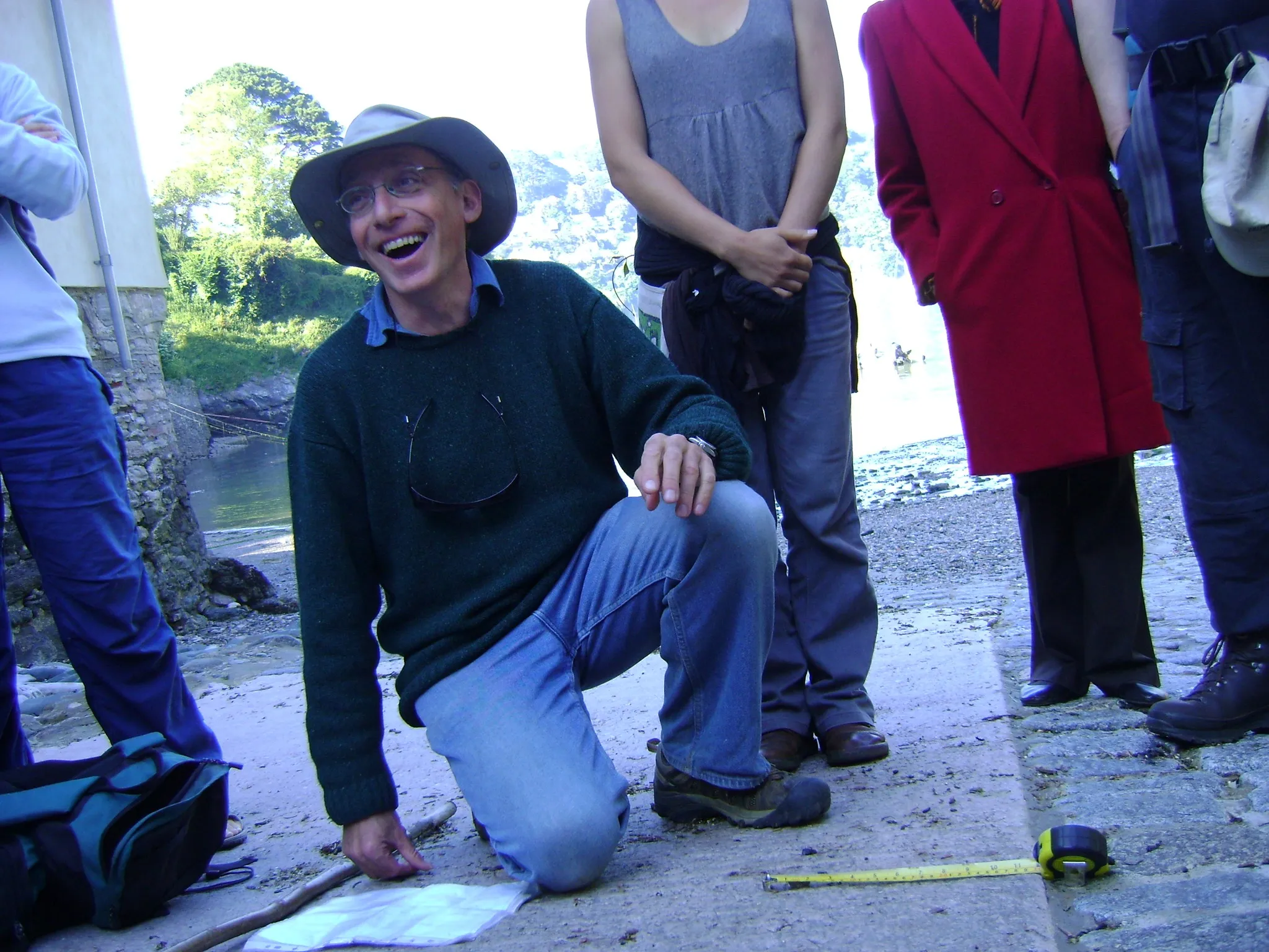 Stephan Harding kneeling and laughing outdoors with students